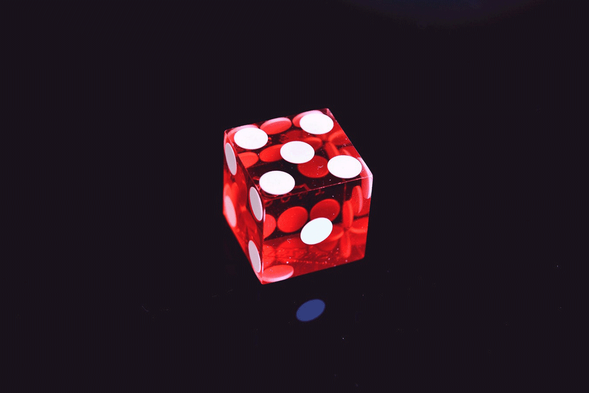 A red dice with white polka dots, perfect for board games and gambling.
