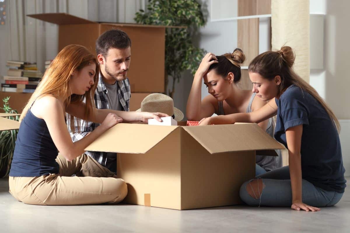 4 young people sitting on the floor in a box, engaged in conversation and displaying a sense of camaraderie.