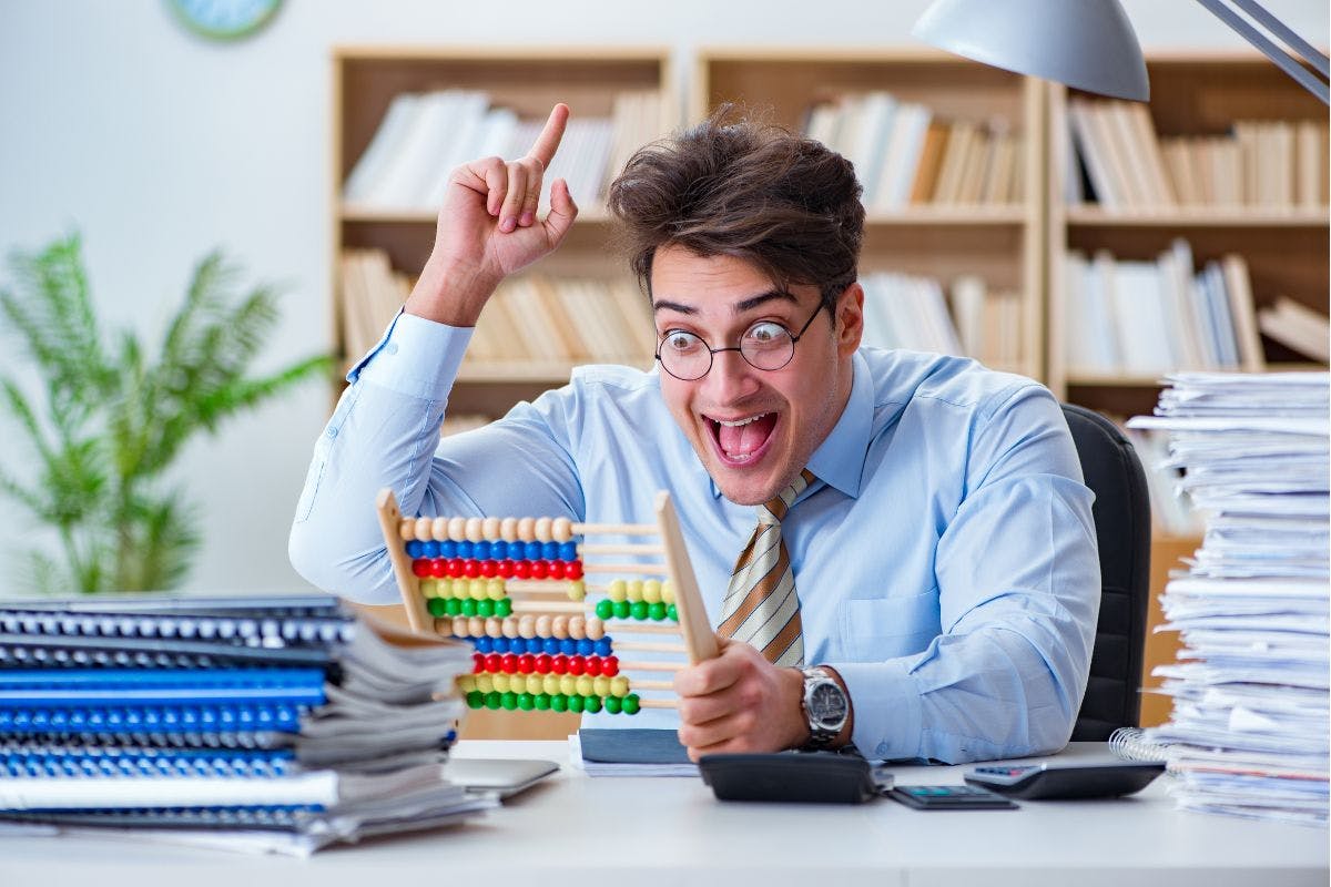 A business man sitting at a desk covered in stacks of paper. He is holding an abacus with a Eureka look on his face.